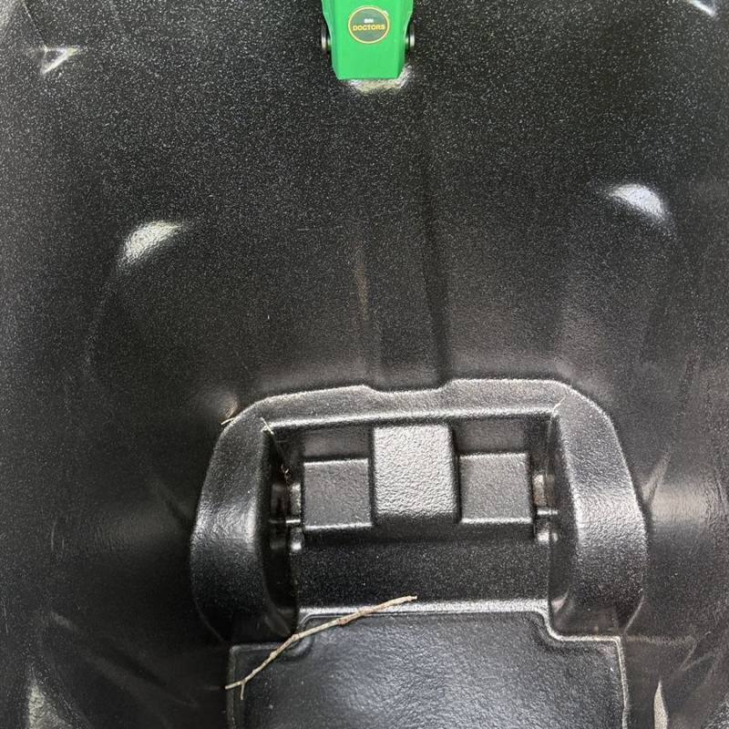 Inside of a trash bin after cleaning: spotless black plastic with a green deodorizer tag