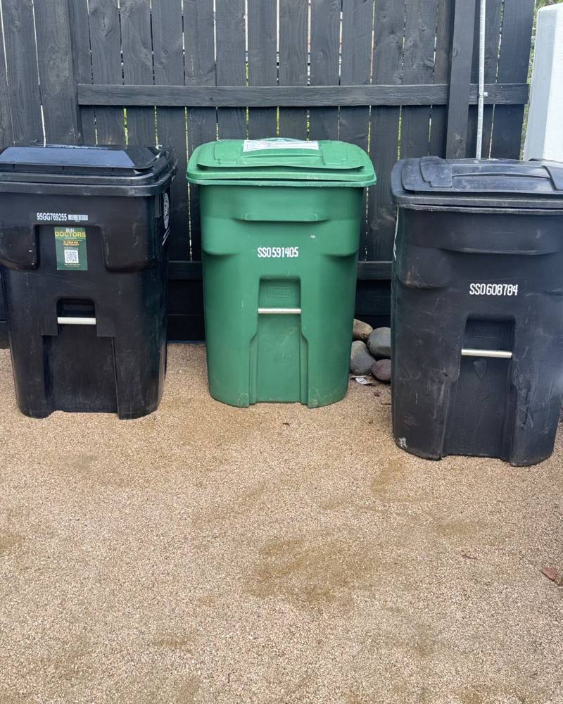 Three clean bins lined up by a fence