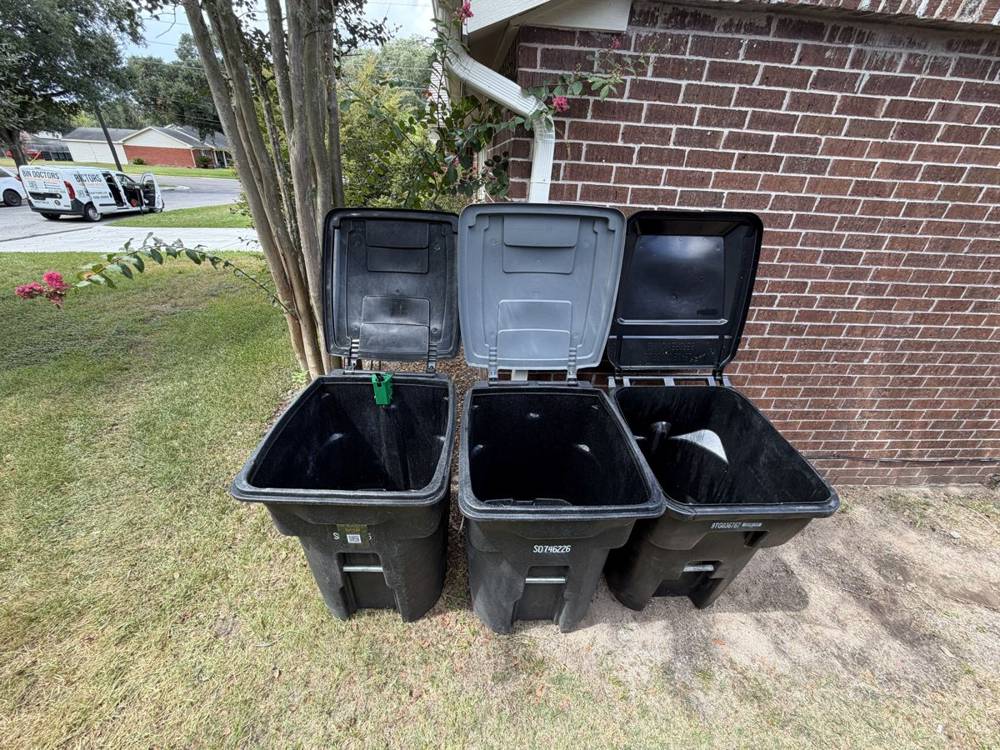 Three clean bins lined up against a brick house
